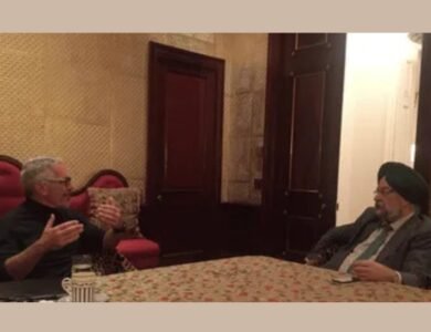 Hardeep Singh Puri seated across a table from Jeffrey Epstein