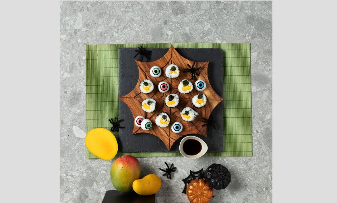 Mango sushi rolls arranged like a caterpillar with nori eyes for Halloween