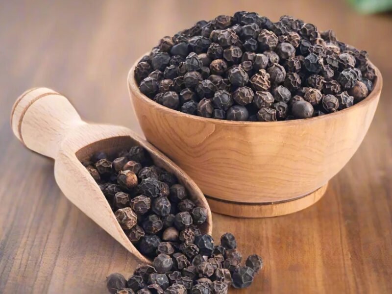 Whole black peppercorns beside ground black pepper
