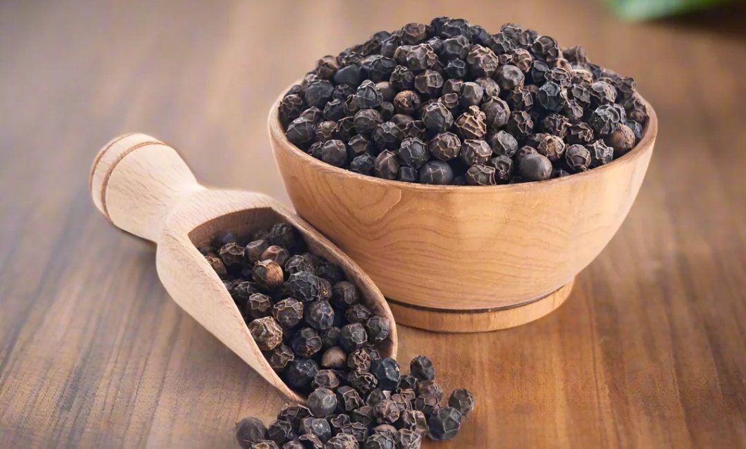 Whole black peppercorns beside ground black pepper